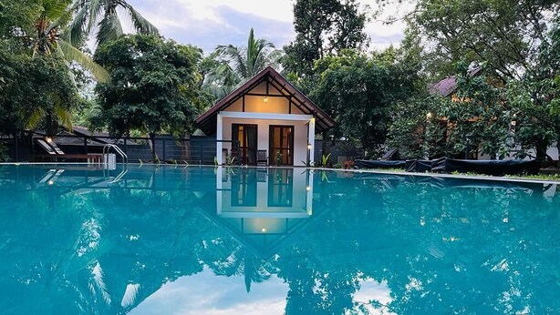 A swimming pool with a reflection of trees and a building in the background. - The Countryside Udawalawe (Udawalawa)