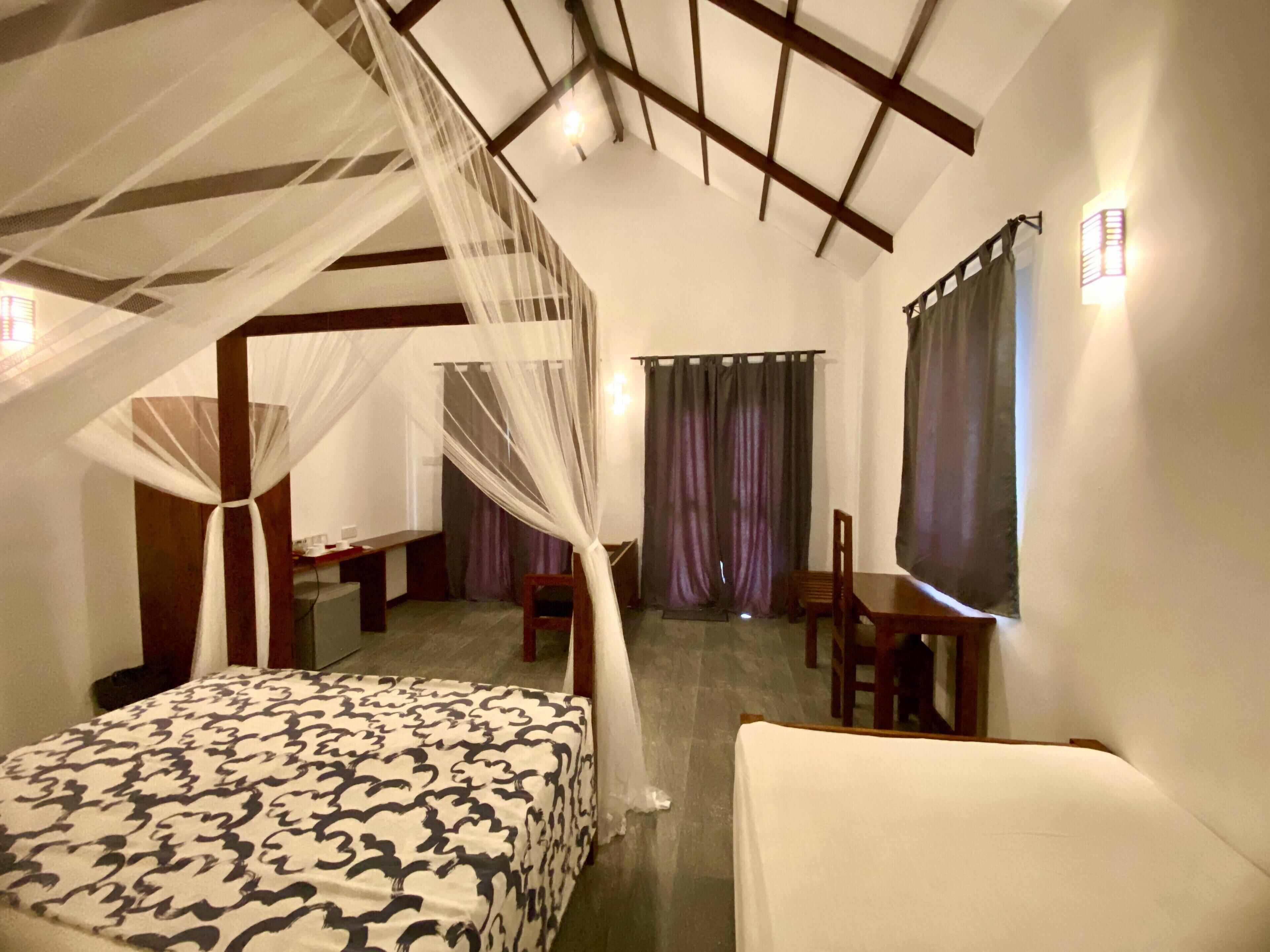 A bedroom with a canopy bed, a desk, and a chair.