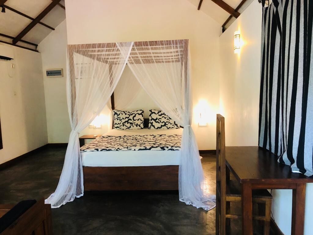 Una habitación con una cama bajo un dosel, una mesa de madera y una silla.