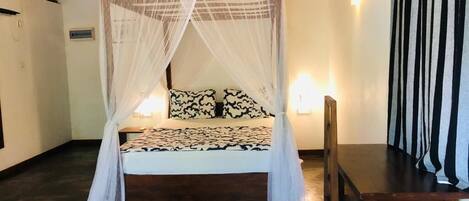Una habitación con una cama bajo un dosel, una mesa de madera y una silla.
