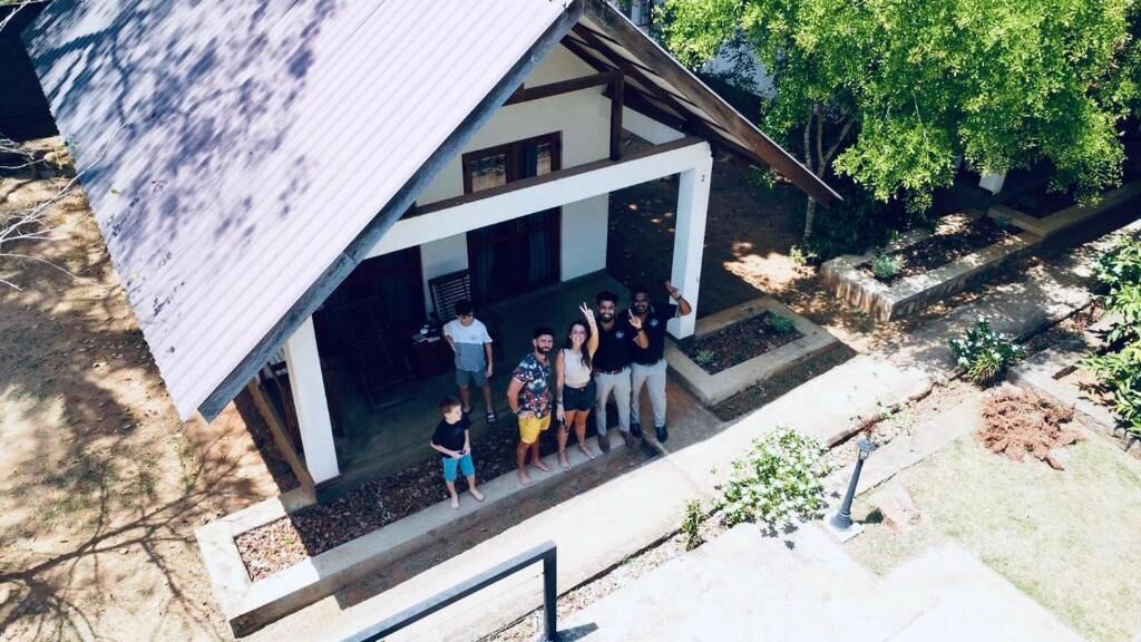 Una casa de dos pisos con un porche cubierto, un pequeño jardín y una escalera visible.