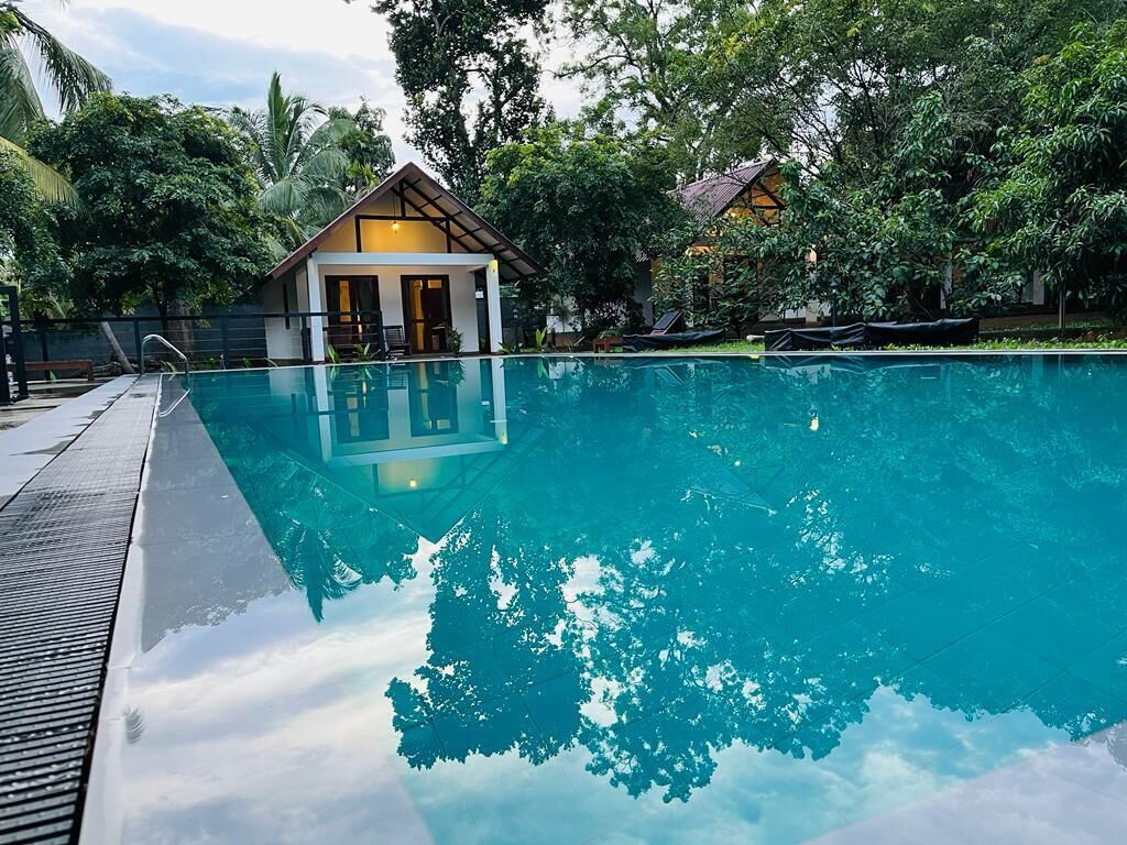 Una piscina con una vista despejada del entorno, incluyendo un edificio con tejado inclinado y una estructura más pequeña con tejado de tejas.