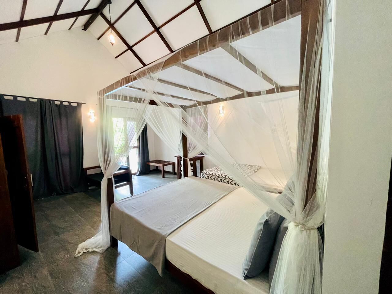 A four-poster bed with a canopy, a wooden headboard, and a bedside table with a lamp.
