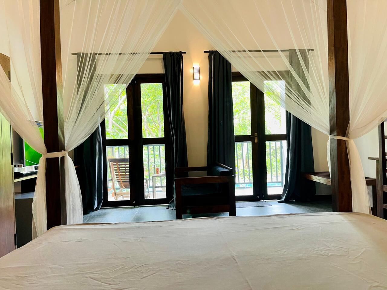 Un dormitorio con una cama grande, televisión y vistas al exterior a través de amplios ventanales.