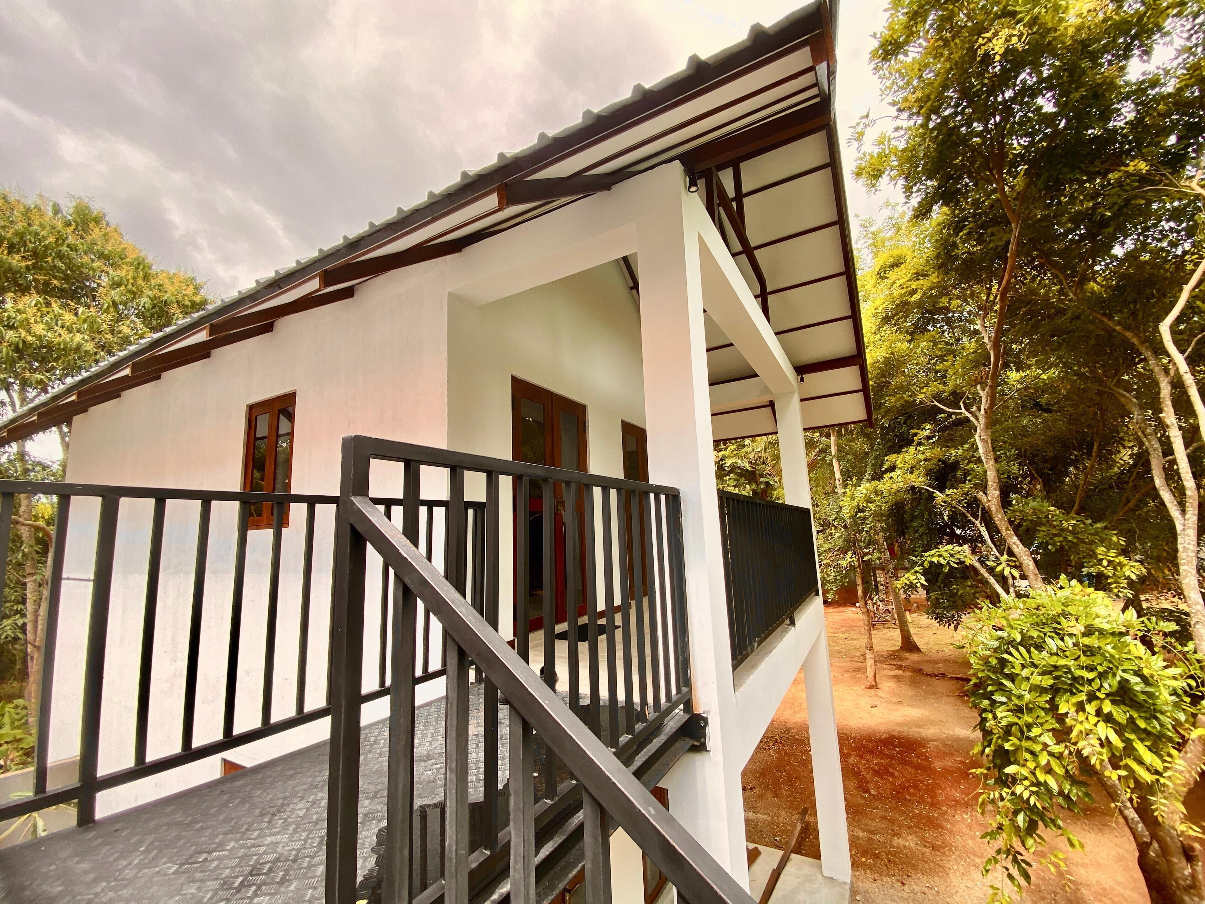 A white building with a covered porch and a staircase leading to an upper level.