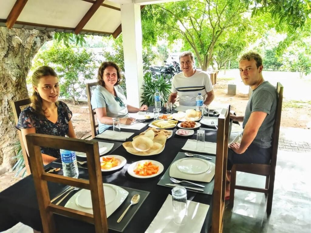 A group of people dining at an outdoor table with various dishes and drinks.