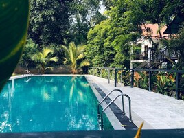 Una piscina al aire libre, sombrillas, sillones reclinables de piscina