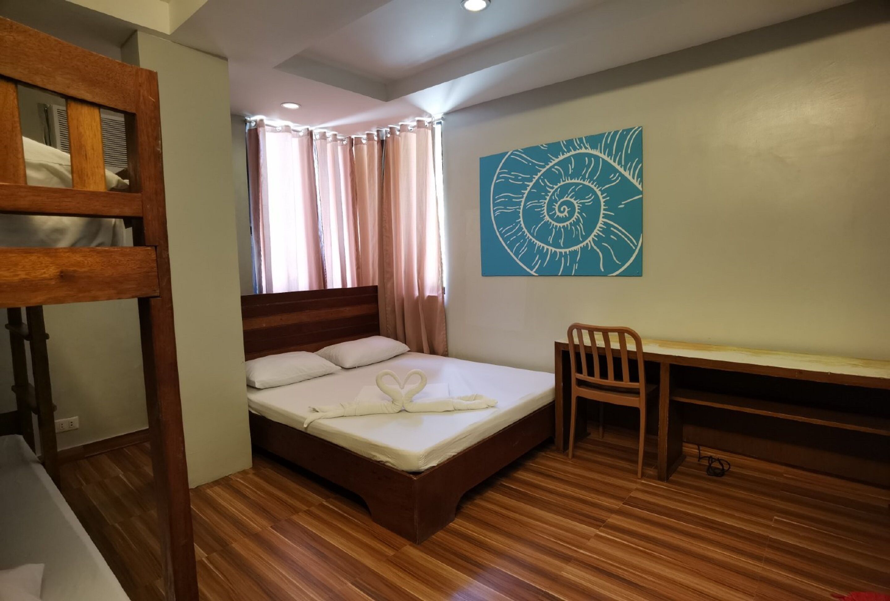 A room with a wooden bed, a desk, and a wall-mounted artwork.