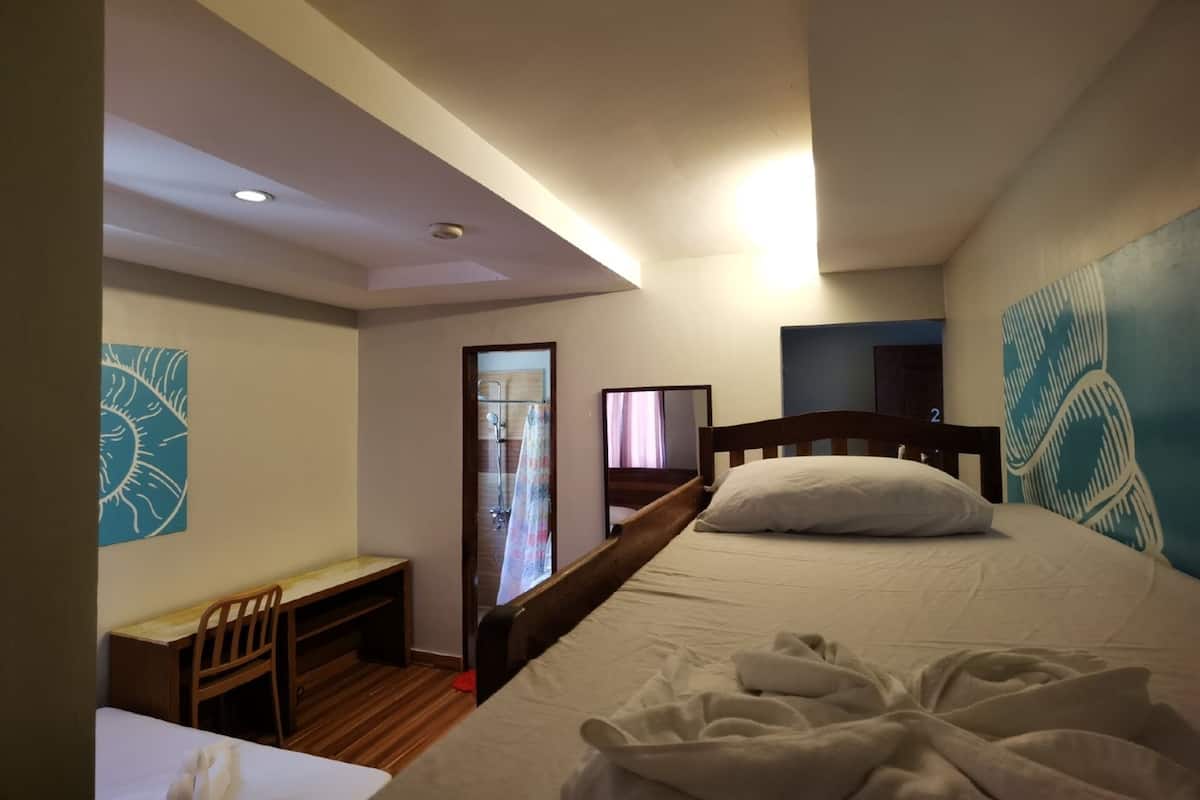 A bedroom with a bed, a desk, and a chair. There is a door leading to a bathroom.