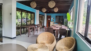 A spacious indoor area with wicker furniture, large windows, and a ceiling with woven light fixtures. - Amos Pili Tree Inn powered by Cocotel (El Nido)