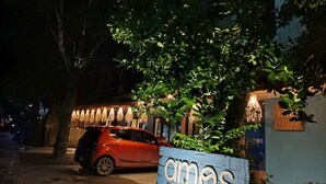 A sign for 'Amos Peli Tree Inn El Nido' with a red car parked nearby. - Amos Pili Tree Inn powered by Cocotel (El Nido)