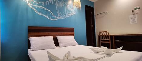 Una habitación de hotel con una cama, almohadas blancas, cabecero de madera, un escritorio y una silla.