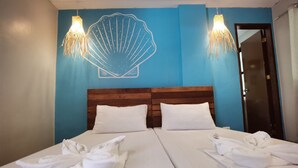 A hotel room with two beds, white linens, a wooden headboard, and a blue accent wall with a shell design. - Amos Pili Tree Inn powered by Cocotel (El Nido)