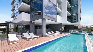 A modern building with a rooftop pool, white lounge chairs, and a clear blue sky. - Sandbar Burleigh (Burleigh Heads)