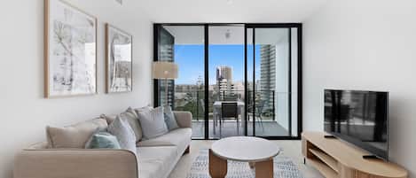 A modern living room with a sofa, coffee table, TV, and artwork on the wall.