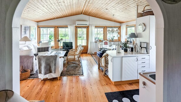 A spacious living area with a wooden ceiling, a dining table, and a kitchen area with white cabinets and a sink. - Stunning home in Borgholm with WiFi (Borgholm)