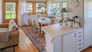 A cozy kitchen with a dining area, wooden flooring, and a view of the garden through large windows. - Stunning home in Borgholm with WiFi (Borgholm)