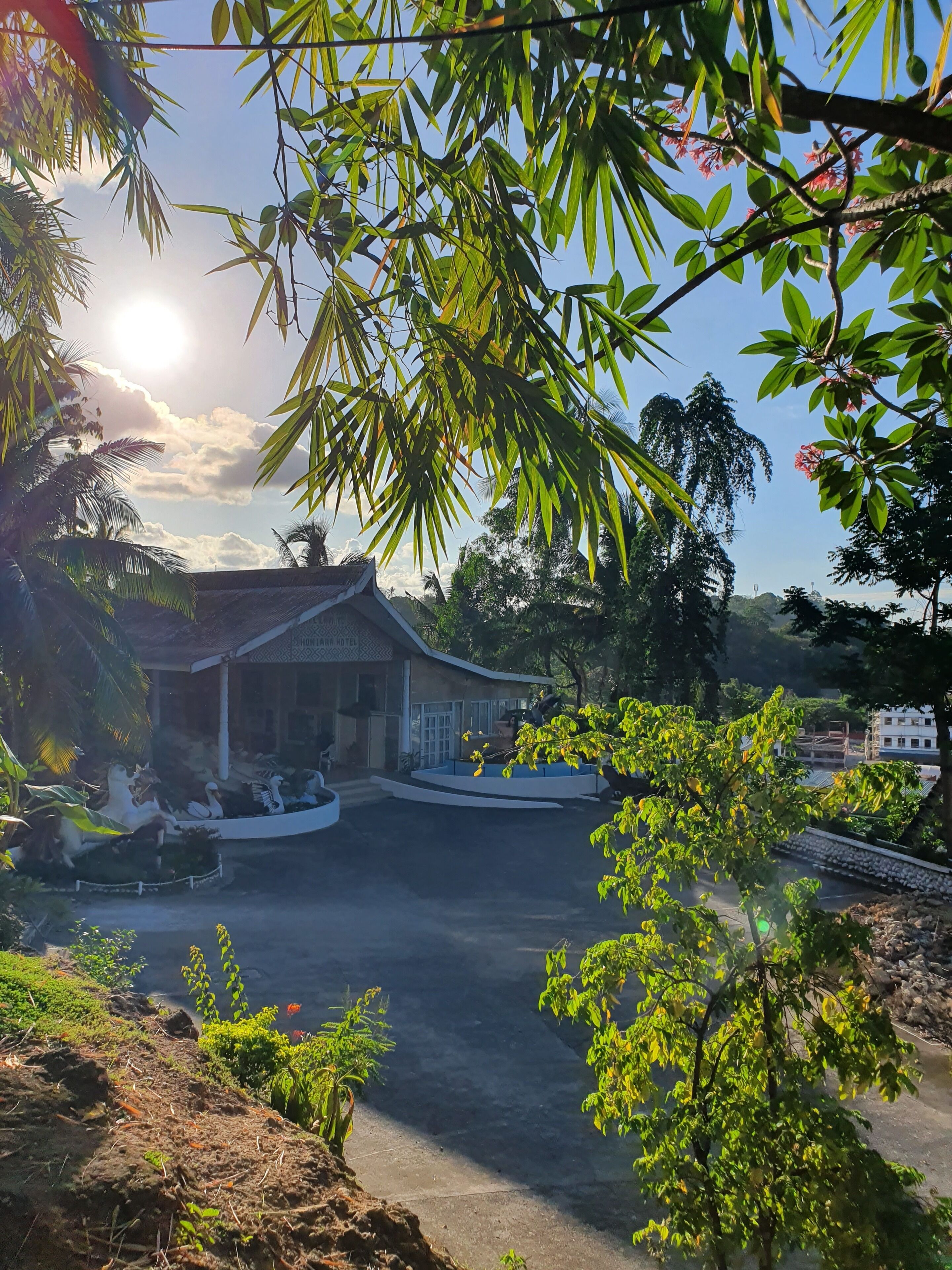 A traditional-style building with a covered entrance, a landscaped garden with swan statues, and a clear view of the sky.