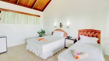Habitación de hotel con dos camas, techo de madera, una planta pequeña y una mesita de noche con un teléfono.