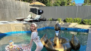 Een zwembad met ligbedden en een decoratieve zwanen drijver.