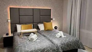 Een moderne hotelkamer met een groot bed, twee kussens, een nachtkastje en een bijzettafeltje.
