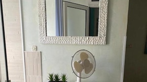 A room with a white dresser, a wall-mounted mirror, a small fan, and a potted plant. - Villa Kolorina (Dubrovnik)