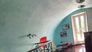 A room with a staircase leading to a landing, a dining area with a table and chairs, and a door leading outside. - Villa Kolorina (Dubrovnik)