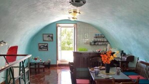 An arched dining area with wooden chairs and tables, a tiled floor, and a view of the outdoors through a doorway. - Villa Kolorina (Dubrovnik)