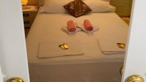 A hotel room with a neatly made bed, a bedside lamp, and a wall-mounted light fixture. - Villa Kolorina (Dubrovnik)