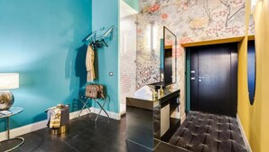 A modern bathroom with a teal wall, a mirror, a black door, and a patterned floor. - Premium Private Suites (Rome)