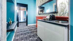 A modern kitchen with a black and white patterned floor, a red countertop, and a large mirror above the sink. - Premium Private Suites (Rome)