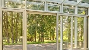 Una habitación con grandes puertas de cristal que dan a un espacio exterior con árboles y un camino de piedra.