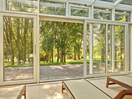 Una habitación con grandes puertas de cristal que dan a un espacio exterior con árboles y un camino de piedra.