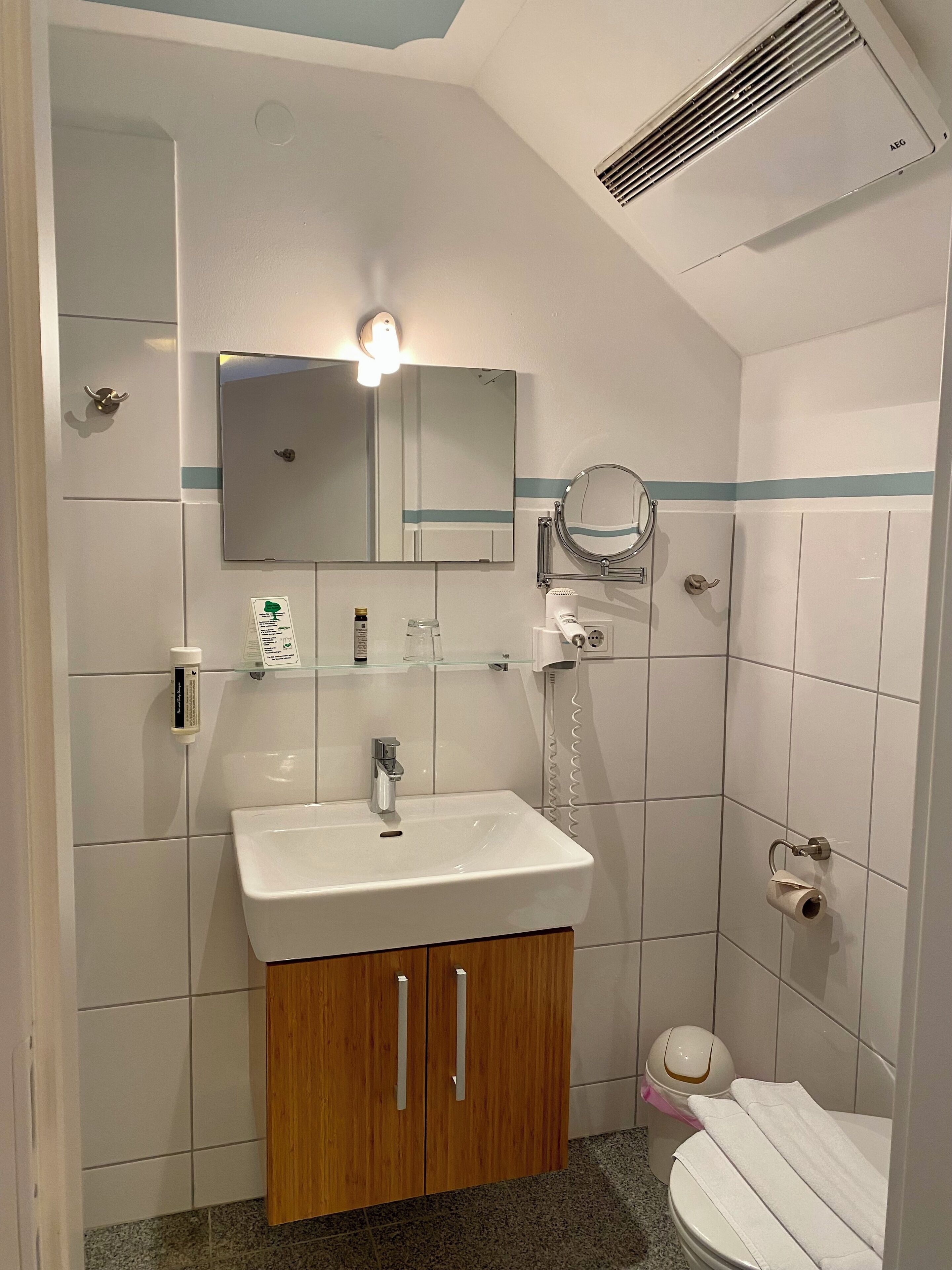 A bathroom with a white sink, wooden cabinet, mirror, and a towel rack.
