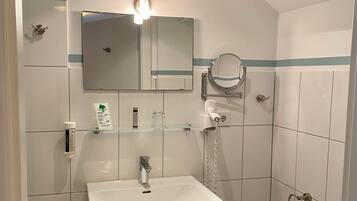 A bathroom with a white sink, wooden cabinet, mirror, and a towel rack.