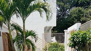 A rectangular swimming pool with clear blue water, surrounded by a white building with a modern design, palm trees, and a gated entrance. - Tranquil Beachside Retreat With Private Pool in Garabito (Tárcoles)