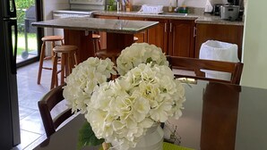 A kitchen with a dining area, a window with a view, and a vase with flowers on the table. - Tranquil Beachside Retreat With Private Pool in Garabito (Tárcoles)