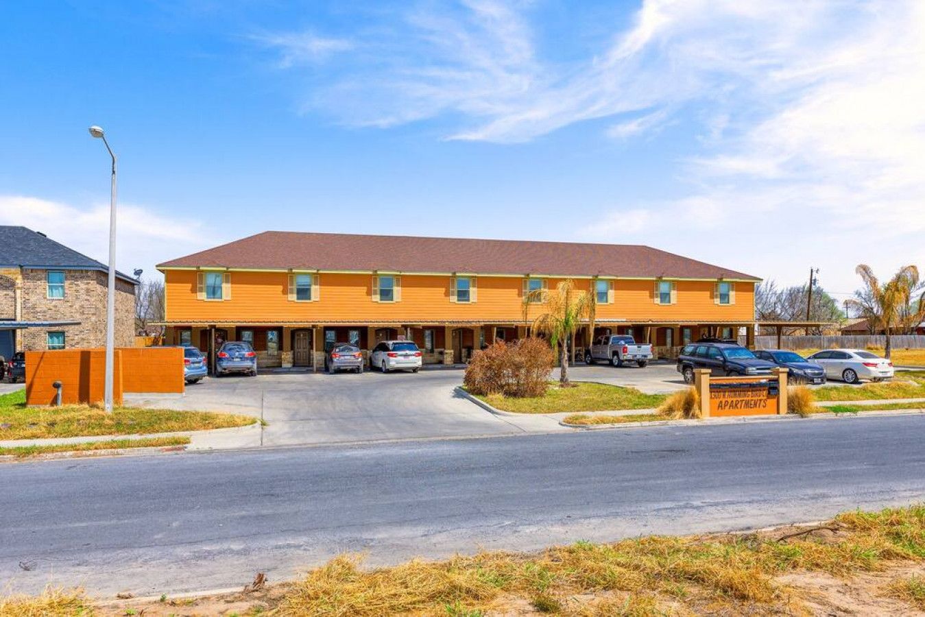 Een motel met meerdere verdiepingen, een centraal parkeergebied en een bord waarop 'EAST PARKING LOT APARTMENTS' staat.