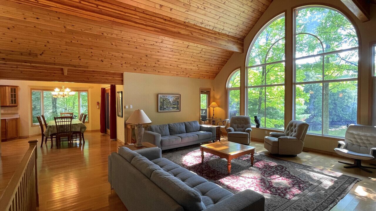 A spacious living room with a high ceiling, large windows, and a cozy seating area.
