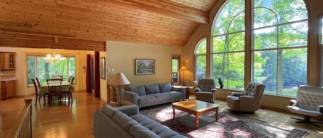 Un salon spacieux avec un plafond haut, de grandes fenêtres et un coin salon confortable.