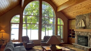 Una sala de estar acogedora con ventanas arqueadas amplias, asientos cómodos, una chimenea y una pared de acento de piedra.