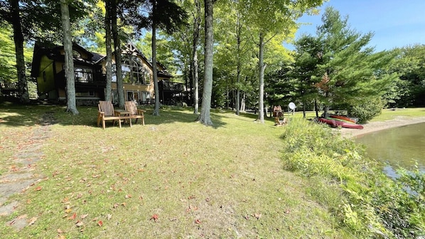 A lodge with a wooden exterior, a deck, and a pond.