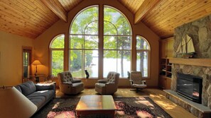 A cozy living room with a fireplace, large windows, and comfortable seating. - Chandos Lake Sanctuary (North Kawartha)
