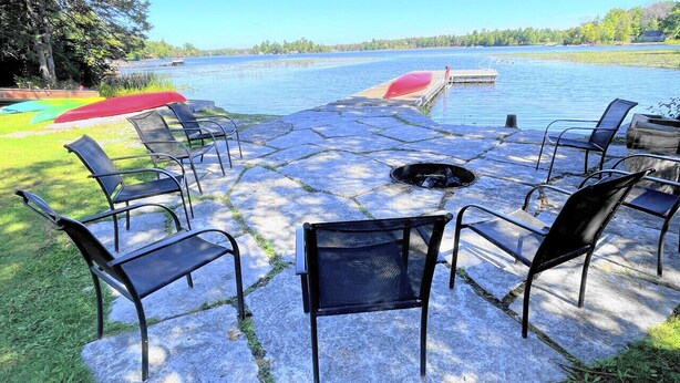 Une terrasse en pierre avec des sièges d’extérieur et un foyer.