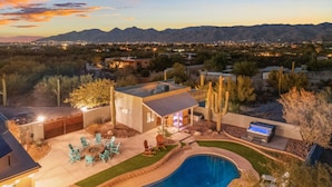 A modern house with a pool, patio furniture, and a view of mountains.