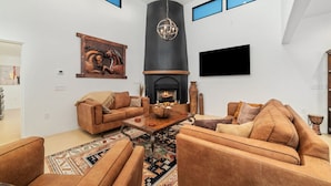 A spacious living room with a fireplace, leather sofas, a coffee table, and a large rug.