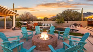 A patio with a fire pit, outdoor seating, and a pool.