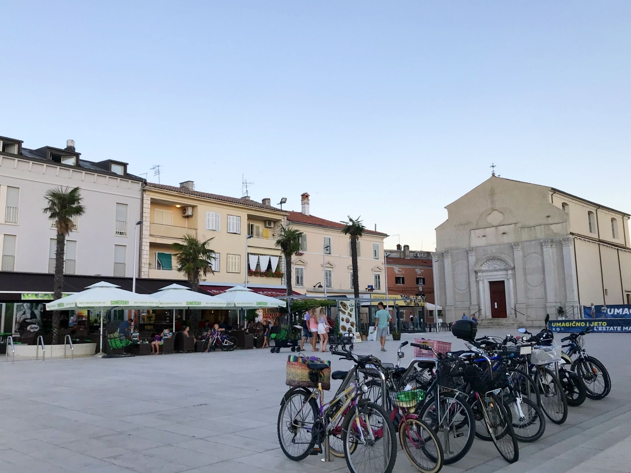 A public square with a row of bicycles parked in front of a building with classical architecture.