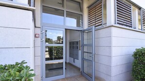 A modern building entrance with a glass door and a small garden area. - Comfortable apartment near the beach Umag (Umag)