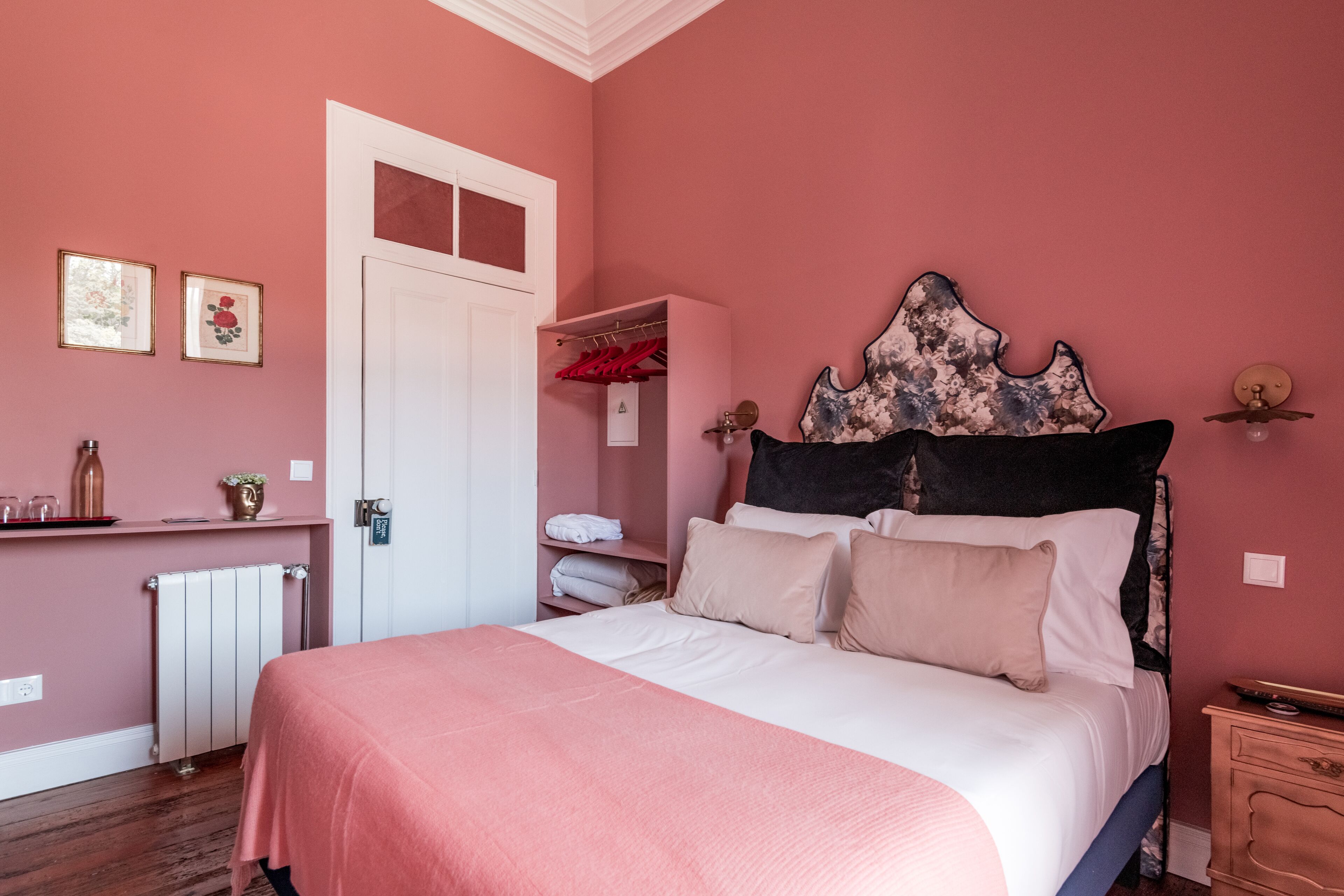 A bedroom with a bed, a wardrobe, a radiator, and a shelf with decorative items.